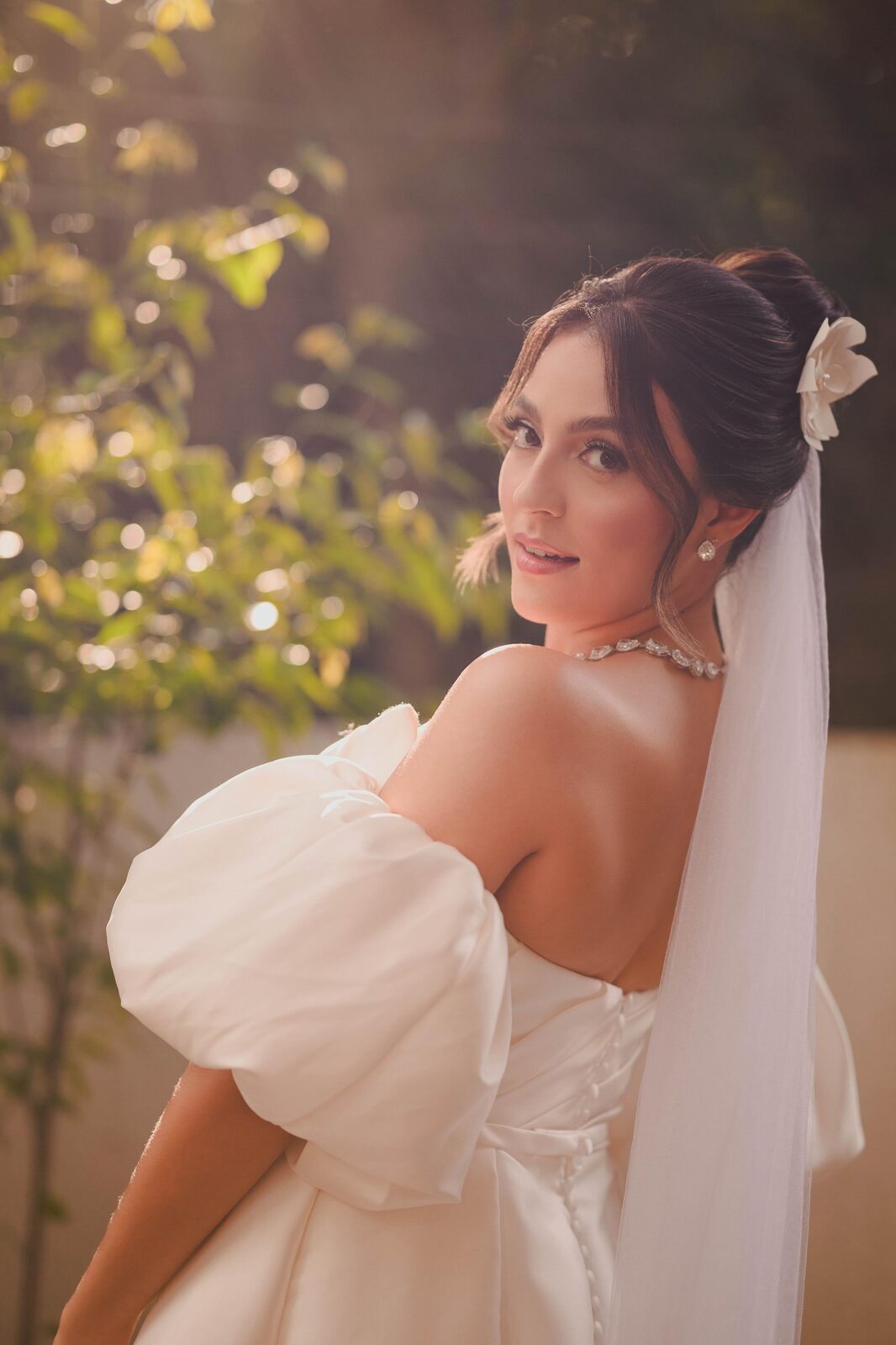 Close editorial da noiva com mangas bufantes sob luz dourada do jardim