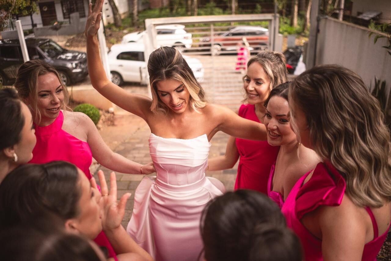 Noiva rodeada por madrinhas em vestidos rosé em celebração ao ar livre