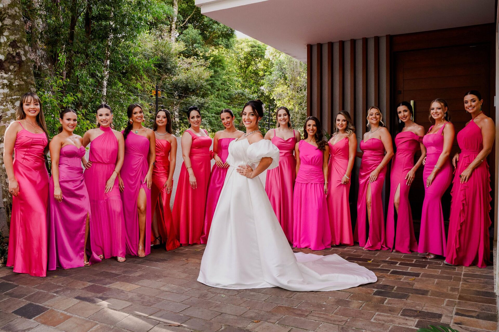 Noiva ao centro ladeada por madrinhas em vestidos rosé em frente ao bosque — Salão do Bosque