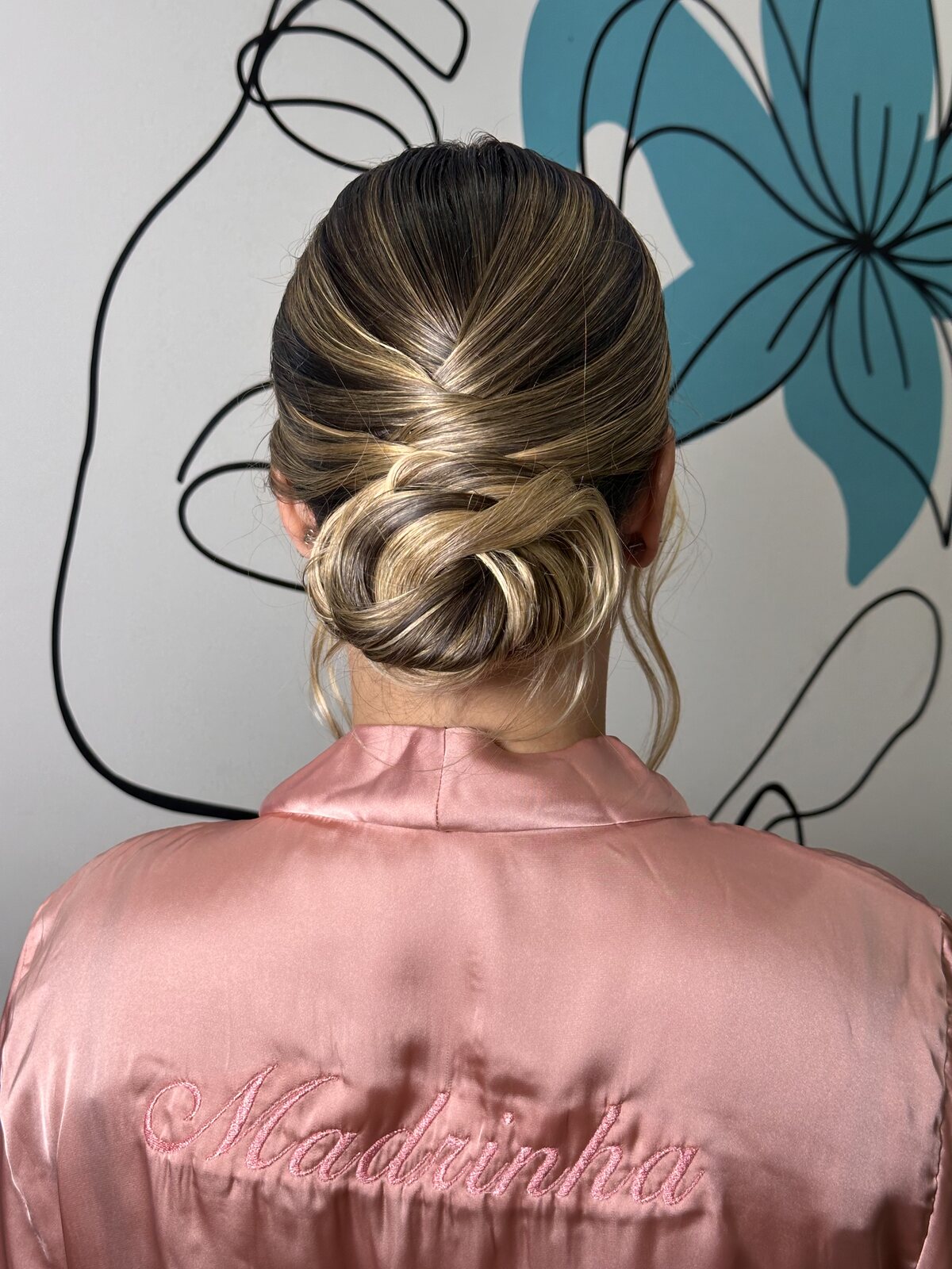 Vista de costas de madrinha com updo balayage e robe rosé com 'Madrinha' bordado — Salão do Bosque